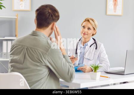 Jeune femme médecin écoutant les plaintes du patient assis en clinique médicale. Banque D'Images