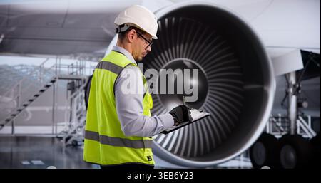 Un technicien portant un casque de sécurité effectue une inspection minutieuse du moteur à réaction à bord de l'avion pendant la maintenance à l'aéroport Banque D'Images
