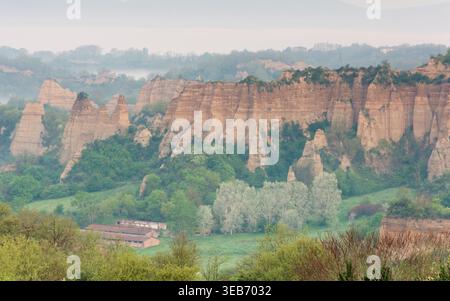 Vue sur les formations rocheuses argileuses de Balze del Valdarno entourées d'une végétation luxuriante et de brume matinale à Piantravigne, Toscane, Italie. Banque D'Images