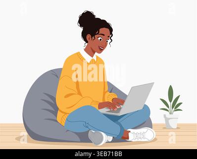 Une jeune femme afro-américaine heureuse est assise les jambes croisées sur une chaise de sac de haricots gris, tapant sur un ordinateur portable avec un sourire concentré. Elle est habillée d'un SW jaune Illustration de Vecteur