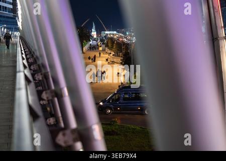 Batumi, géorgie 21 avril 2026 : paysage urbain nocturne de batumi avec promenade éclairée, piétons se promenant et un van conduisant le long de la route éclairée adjacente Banque D'Images