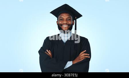 Remise des diplômes, bras croisés et portrait avec homme noir en studio pour le succès, le collège et la bourse. Université, avenir et fierté avec personne sur bleu Banque D'Images