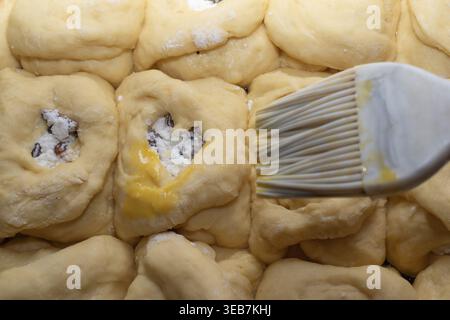 Petits pains sucrés faits maison avec du fromage cottage et des raisins secs avant de cuire le processus de pâtisserie traditionnel Banque D'Images