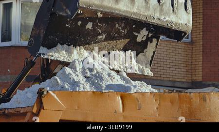 Excavatrice chargeant la neige de la rue dans le camion pendant les opérations de déneigement hivernal Banque D'Images