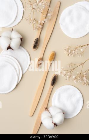 Tampons de coton réutilisables avec brosses à dents en bambou, bornes de coton et fleurs séchées sur fond beige. Concept écologique de soins de la peau et de soins buccaux, zéro w Banque D'Images