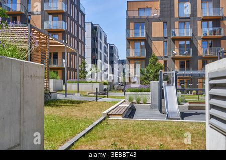 Complexe résidentiel moderne présentant une architecture contemporaine avec des panneaux en bois et des façades sombres. L'image montre une cour commune Banque D'Images