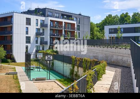 Complexe résidentiel moderne comprenant des bâtiments contemporains à plusieurs étages avec des façades blanches et gris foncé, des accents de balustrade en bois et de grandes Banque D'Images