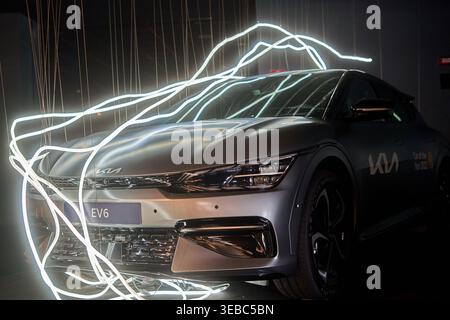 Un SUV crossover électrique Kia EV6 argenté positionné à un angle trois-quarts avant dans un environnement de studio sombre et dramatique. Le véhicule dispose de Banque D'Images