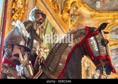 L'image représente une vitrine muséale élaborée mettant en scène deux personnages armés et un cheval caparaçonné, présentant des tenues militaires historiques dans un Banque D'Images