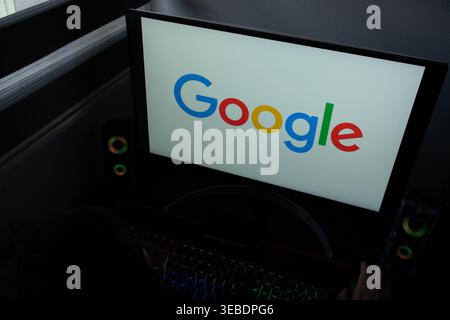 Le logo multicolore de Google est affiché sur un écran d'ordinateur dans un environnement de bureau à domicile sombre Banque D'Images