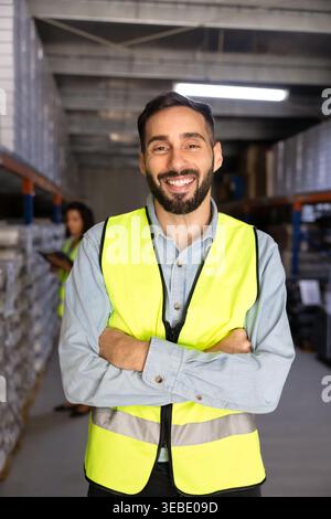 Portrait d'un ouvrier hispanique souriant debout dans un entrepôt Banque D'Images
