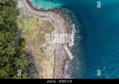 Vue aérienne du site de torpille de la seconde Guerre mondiale à Tomaree Head en Nouvelle-Galles du Sud, Australie, où la côte rocheuse accidentée rencontre l'océan turquoise. Scen Banque D'Images