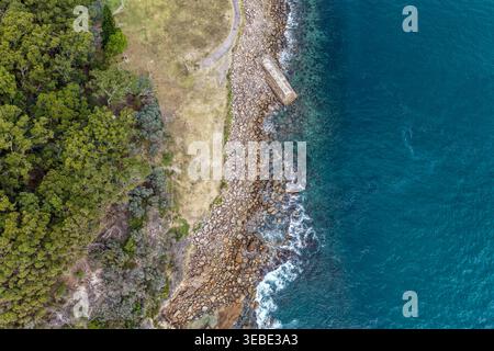 Vue aérienne du site de torpille de la seconde Guerre mondiale à Tomaree Head en Nouvelle-Galles du Sud, Australie, où la côte rocheuse accidentée rencontre l'océan turquoise. Scen Banque D'Images