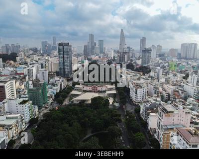 Vue aérienne de l'horizon moderne avec des gratte-ciel et une architecture urbaine dense entourant un parc verdoyant sous un ciel nuageux à Ho Chi Minh C. Banque D'Images
