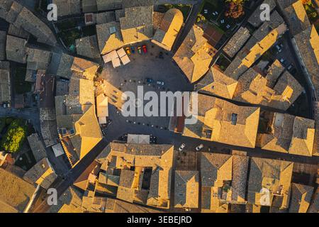 Vue aérienne de la place de la ville circulaire historique entourée d'anciens bâtiments en pierre et toits carrelés pendant l'heure d'or à Montefalco, Ombrie, IT Banque D'Images