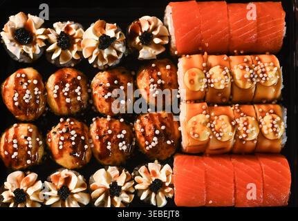 assortiment de sushis avec rouleaux et nigiri disposés en rangées, morceaux de sushis recouverts de poisson et de sauce, variété de fruits de mer colorés sur l'assiette, détail en gros plan, j Banque D'Images