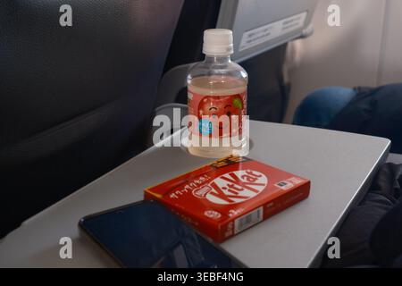 En-cas à bord avec jus de pomme japonais et bar KitKat sur une table d'avion. Banque D'Images