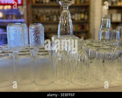 Verrerie renversée sur une étagère dans un bar ou un restaurant avec diverses bouteilles de boisson en arrière-plan. Photo mobile Banque D'Images