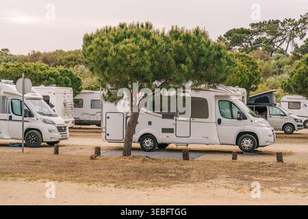 Manta Rota, Portugal, 23 avril 2026. Camping-car blanc stationné sous un pin dense dans un camping en plein air paisible avec d'autres véhicules à proximité Banque D'Images