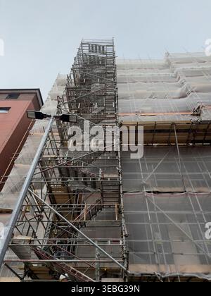Échafaudage de construction haute avec escaliers à côté du bâtiment en rénovation Banque D'Images