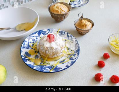 Mini gâteau citron Bundt avec Curd et framboises. La tendance de la pâtisserie méditerranéenne authentique met l'accent sur les ingrédients biologiques naturels et les agrumes vibrants Banque D'Images