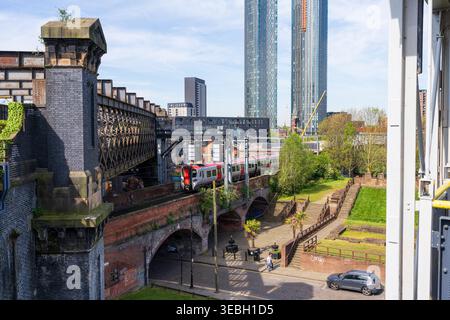 Manchester, Royaume-Uni, 25 avril 2026 : train voyageant sur un viaduc de briques au-dessus du canal avec des gratte-ciel modernes surplombant le fort romain historique Banque D'Images