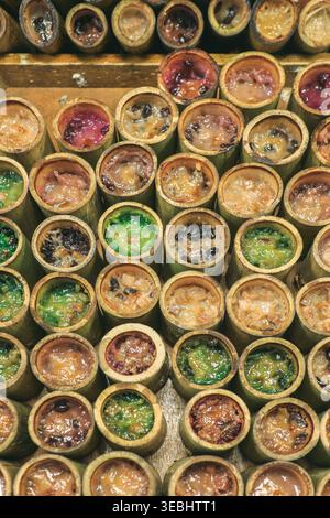 Vue de dessus du riz collant khao Lam en bambou disposé en rangées au marché thaïlandais montrant la culture traditionnelle des desserts et de la Street food. Banque D'Images