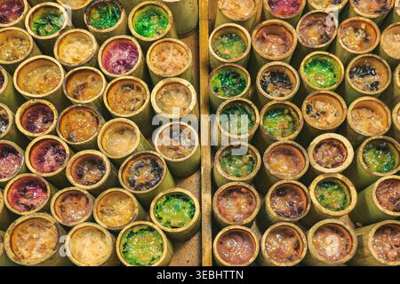 Vue de dessus du riz collant khao Lam en bambou disposé en rangées au marché thaïlandais montrant la culture traditionnelle des desserts et de la Street food. Banque D'Images
