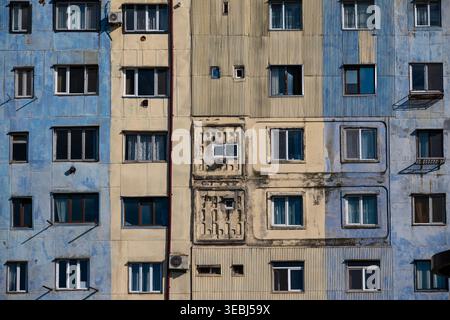 Vue symétrique des murs d'appartements préfabriqués altérés, montrant des textures de panneaux bleus et jaunes Banque D'Images