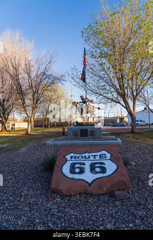Panneau historique de la Route 66 peint sur un monument en pierre avec une statue du Pony Express et un drapeau américain sous un ciel bleu à Holbrook, Arizona Banque D'Images