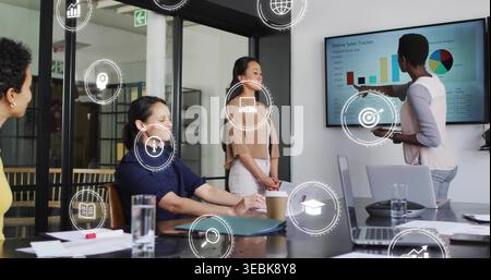 Présentant la femme en blazer beige pointant aux tableaux de vente sur le moniteur dans la salle de réunion avec ordinateur portable Banque D'Images