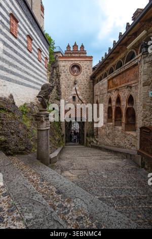 Bologne, Italie - 27 mars 2022 : vue d'une entrée en arche en pierre, encadrée par des murs de pierre altérés et un aperçu de personnages qui passent à travers, où Ligh Banque D'Images