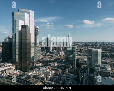 Vue aérienne des gratte-ciels en verre perçant la ligne d'horizon, contrastant avec l'architecture historique ci-dessous, baignée dans la douce lueur de la lumière du jour, ville de Banque D'Images