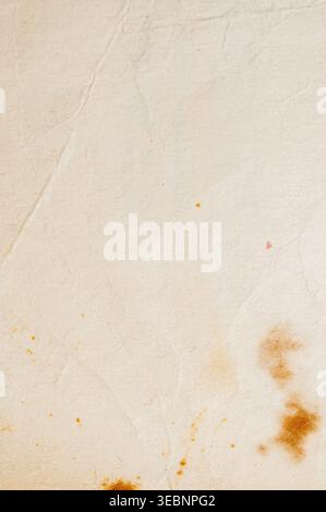 Vue rapprochée d'une surface texturée de papier blanc cassé montrant des signes d'âge, y compris des taches brunes et de faibles lignes de pliage Banque D'Images