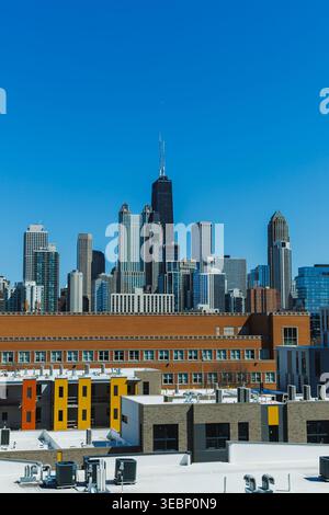 Une vue dégagée du centre-ville de Chicago montre de grands bâtiments et structures. Le soleil brille brillamment sur la ligne d'horizon, avec des toits au premier plan. Banque D'Images