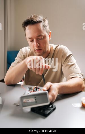 Plan vertical d'un technicien effectuant une réparation d'ordinateur, utilisant un tournevis pour réparer le matériel électronique ouvert, en entretenant les composants du dispositif à Banque D'Images