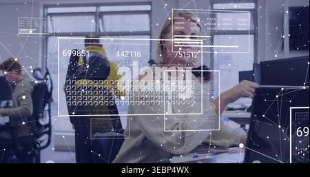 Atteindre la femme mature avec des lunettes et un pull léger touchant le moniteur dans le bureau ouvert, superpositions de données Banque D'Images