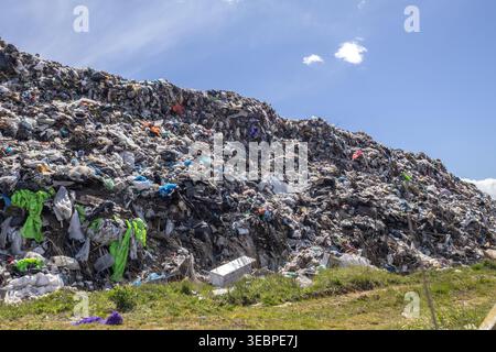 Un grand site d'enfouissement montre des tas de déchets et d'ordures avec différentes couleurs visibles sous le ciel lumineux pendant la journée. Banque D'Images