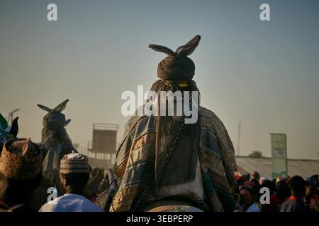 Zaria City, Nigeria - 22 mars 2026 : vue d'une figure éminente dans une tenue traditionnelle élaborée avec des couvre-chefs à cornes distinctifs, au milieu d'une cr animée Banque D'Images