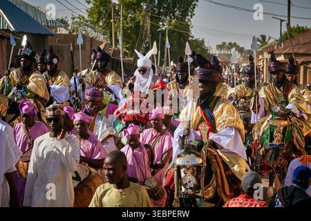 Zaria City, Nigeria - 22 mars 2026 : vue d'une procession cérémonielle vibrante de cavaliers dans une tenue dorée resplendissante et d'une foule en rose vif, animée Banque D'Images
