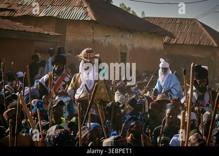 Zaria, Nigeria - 22 mars 2026 : vue d'hommes à la décoration traditionnelle, leurs robes riches et leur personnel contrastant avec les murs texturés et cuits au soleil des maisons Banque D'Images
