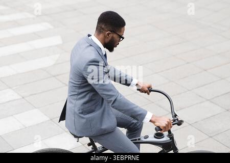 Cycliste élégant en tenue habillée naviguant dans les rues de la ville pendant la journée Banque D'Images