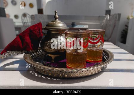 Cérémonie du thé marocaine servant du thé à la menthe fraîche à partir d'une théière en argent gravée dans des verres ornés, représentant l'hospitalité et la culture Banque D'Images