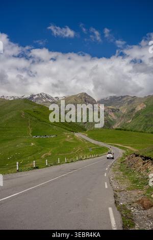 Route de montagne pittoresque à Kazbegi, Géorgie. Autoroute asphaltée sinueuse à travers les montagnes vertes du Caucase avec voiture blanche, aventure Road trip, liberté et concept de voyage alpin Banque D'Images
