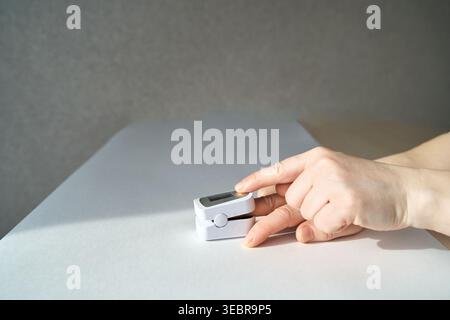 Petit oxymètre de pouls réglable à deux mains empilé sur un plan d'examen blanc dans une pièce intérieure avec lumière latérale douce et fond neutre. Banque D'Images