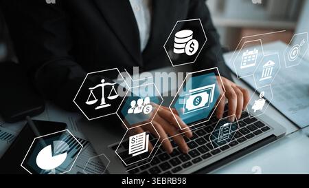 Professionnel travaillant sur ordinateur portable avec des icônes numériques de droit et de finance, représentant la technologie juridique moderne et la gestion financière dans une entreprise Banque D'Images