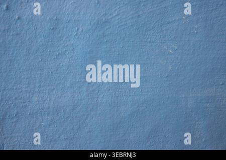 Texture murale peinte en bleu avec une surface rugueuse et inégale et des détails granuleux subtils, parfaite pour les arrière-plans minimalistes ou les superpositions de conception architecturale. Banque D'Images