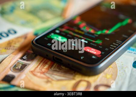 Smartphone montrant l'application de trading avec graphique du marché sur les billets en euros. Concept d'investissement en ligne, de risque financier, de trading mobile et de finance numérique. Banque D'Images