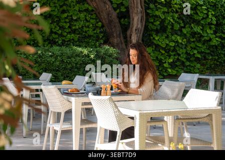 Femme à la table de café avec des fruits et des pâtisseries à Antibes, France Banque D'Images