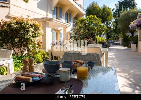 Petit déjeuner terrasse matinale par villa crème avec volets bleus à Antibes Banque D'Images